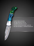 Copper Damascus steel blade pattern detail on blue and green folding knife