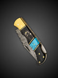Close up of buffalo horn handle with turquoise style inlay and brass fittings