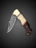 Damascus clip point blade extended on brown and cream lockback folding knife