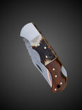 Close up of stag horn and rosewood handle with brass pins on Damascus folding knife