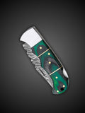 Close up of green and black Pakkawood handle with brass accents on folding knife