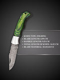 Swirling Damascus steel blade pattern detail on green handcrafted folding knife