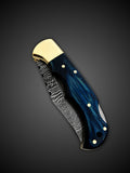 Close up of light blue acrylic handle with brass fittings on Damascus folding knife